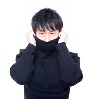 黒いタートルネックの襟を両手で持ち上げるスタジオの人物の写真