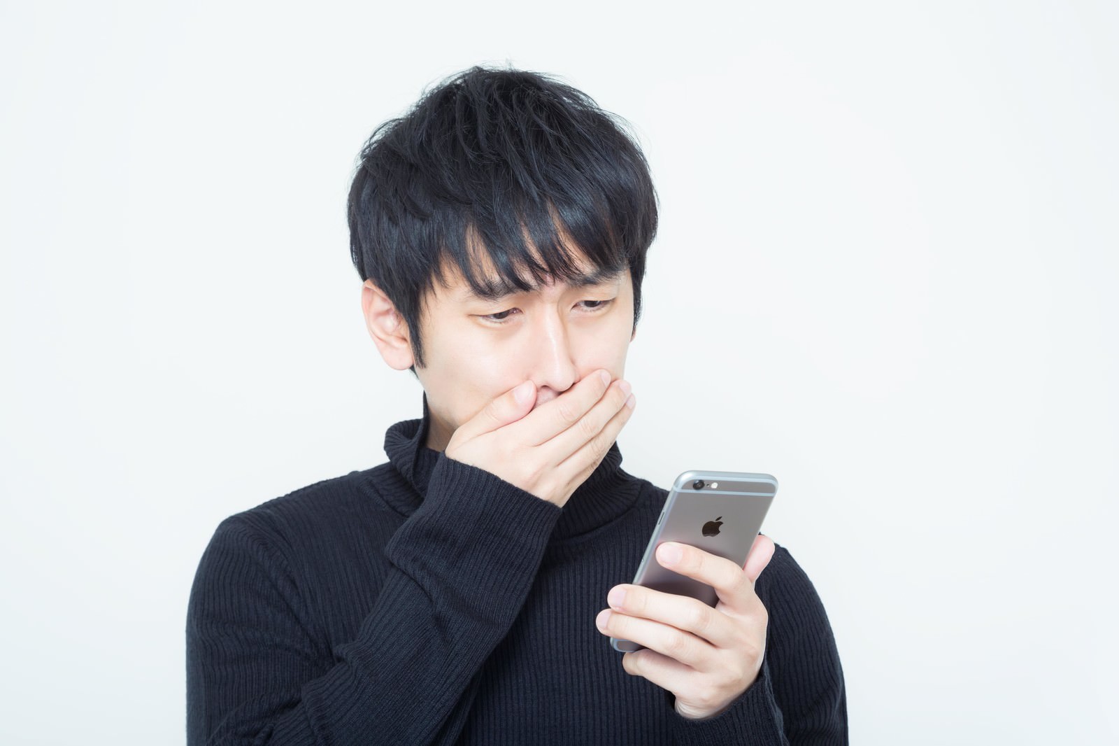 スマホを見て口を覆う男性［モデル：大川竜弥］