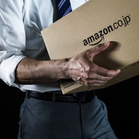 ダンボール箱を抱えて運ぶ総務課の男性の配送業務の写真