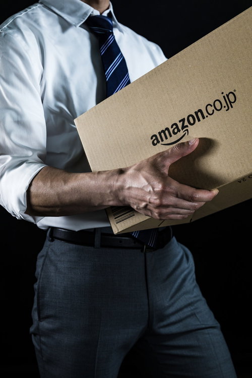 ダンボール箱を抱えて運ぶ総務課の男性の配送業務