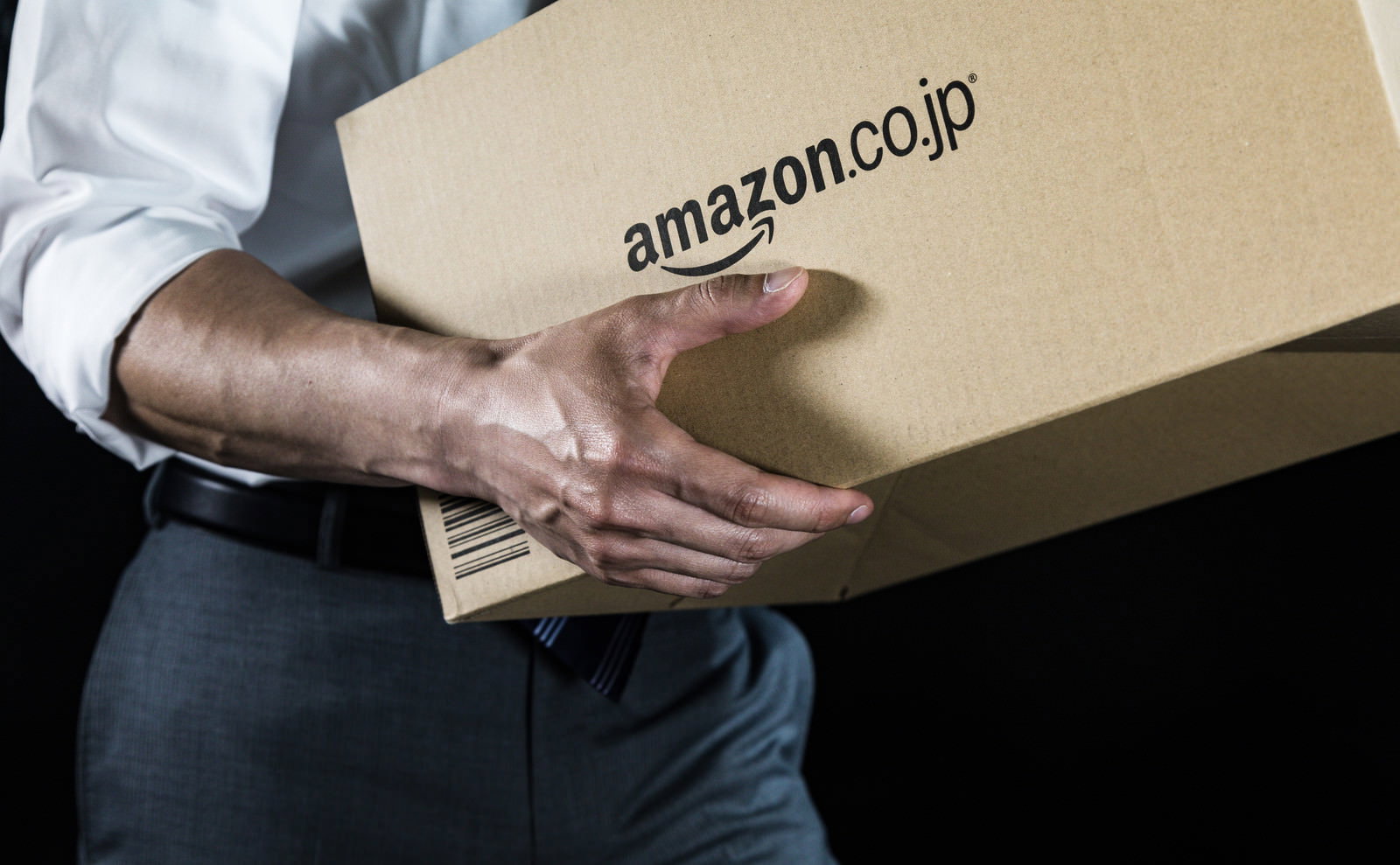 amazon.co.jpの段ボール箱を両腕で抱える男性［モデル：大川竜弥］