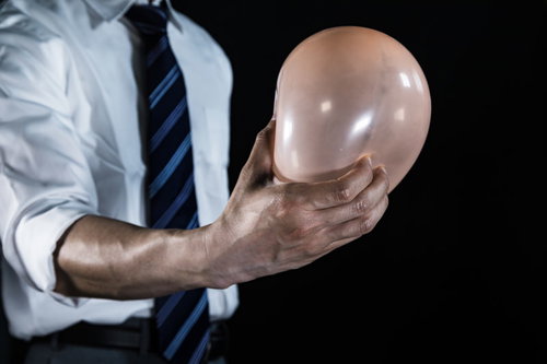 風船を鷲づかみする会社員の手、ビジネスシーンでの決定力を表現