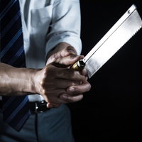 金属製のノコギリを両手で握る会社員の脅迫シーンの写真