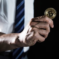 ビットコインのコインを掲げるビジネスマンの写真