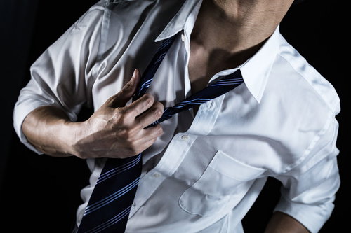 暑さでワイシャツを脱ぐサラリーマン男性、汗をかいた状態