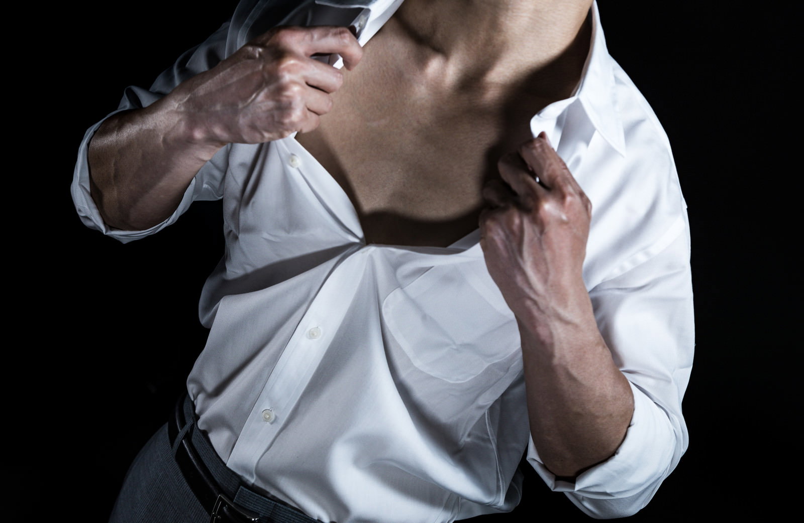 白いワイシャツを引っ張って脱ごうとするサラリーマン男性［モデル：大川竜弥］