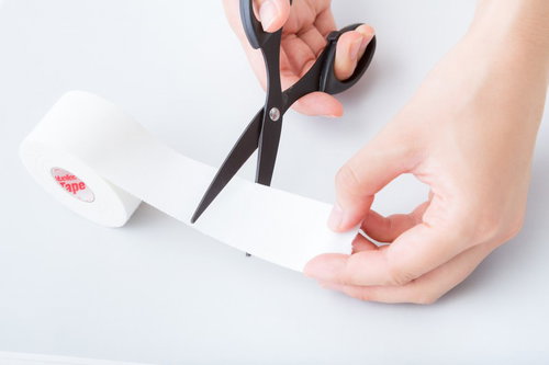 ホワイトテープをハサミでカットする施術準備