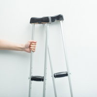 松葉杖を握りしめる手、リハビリテーション中の歩行補助装具の写真