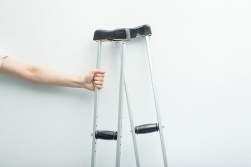 松葉杖を握りしめる手、リハビリテーション中の歩行補助装具