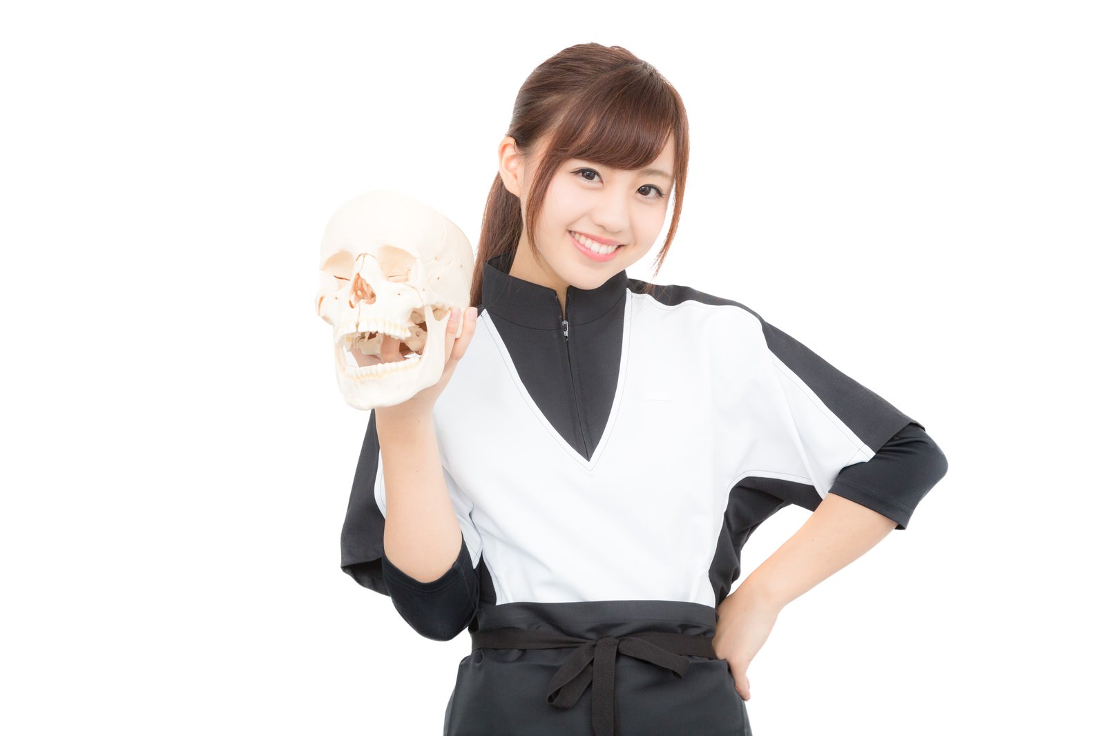 ドクロの人体標本を持って笑顔で立つ女性スタッフ［モデル：河村友歌］