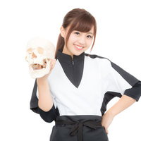 医学標本のドクロを持った笑顔の女性スタッフの写真