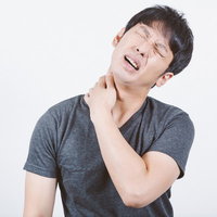 肩こりが酷くて首に手をあてて苦しむ男性の体調管理の写真