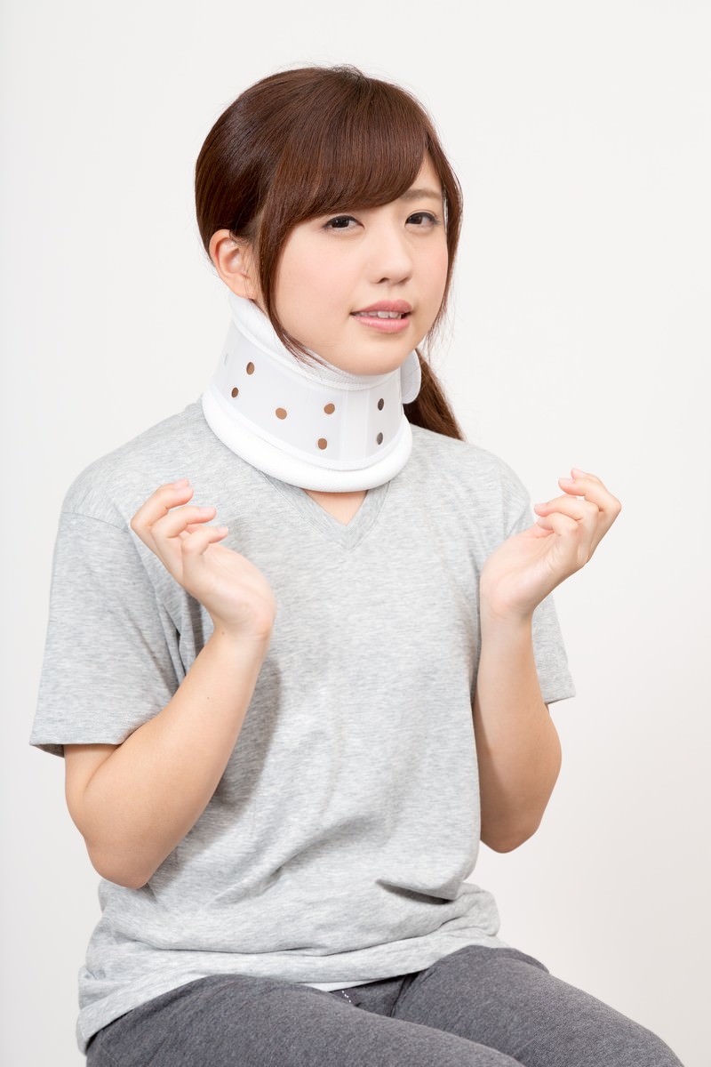 頚椎カラーを装着して首が痛い様子を示す女性［モデル：河村友歌］
