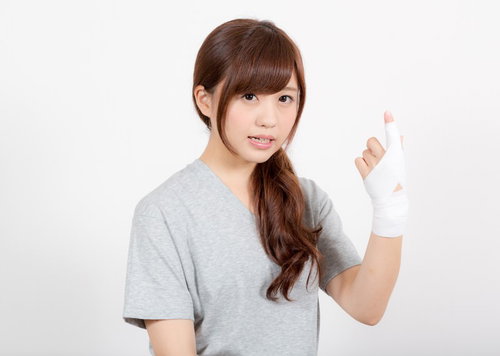 左手の示指を白いテーピングで固定する女性