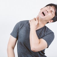 交通事故10日前後のむち打ち症で首と肩の激痛に苦しむ男性の写真