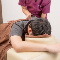 肩のこりをとる施術を受ける男性、整骨院での指圧マッサージの写真