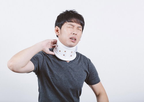 交通事故のむち打ちで首にコルセットを巻いて痛みに顔をしかめる男性
