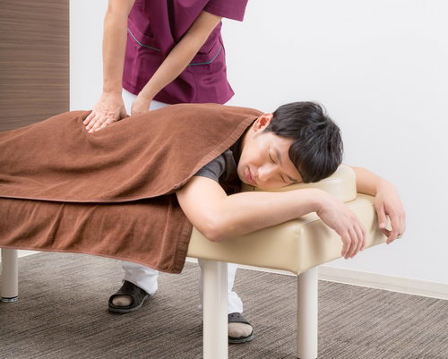 整骨院でマッサージを受けて全身の疲れを取る女性