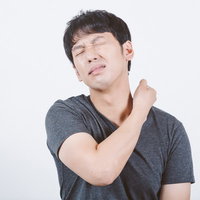 首の痛みや違和感を感じて目をつむる男性の肩こりの写真