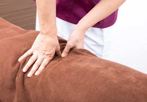 背中のマッサージ施術を受ける女性の指圧治療