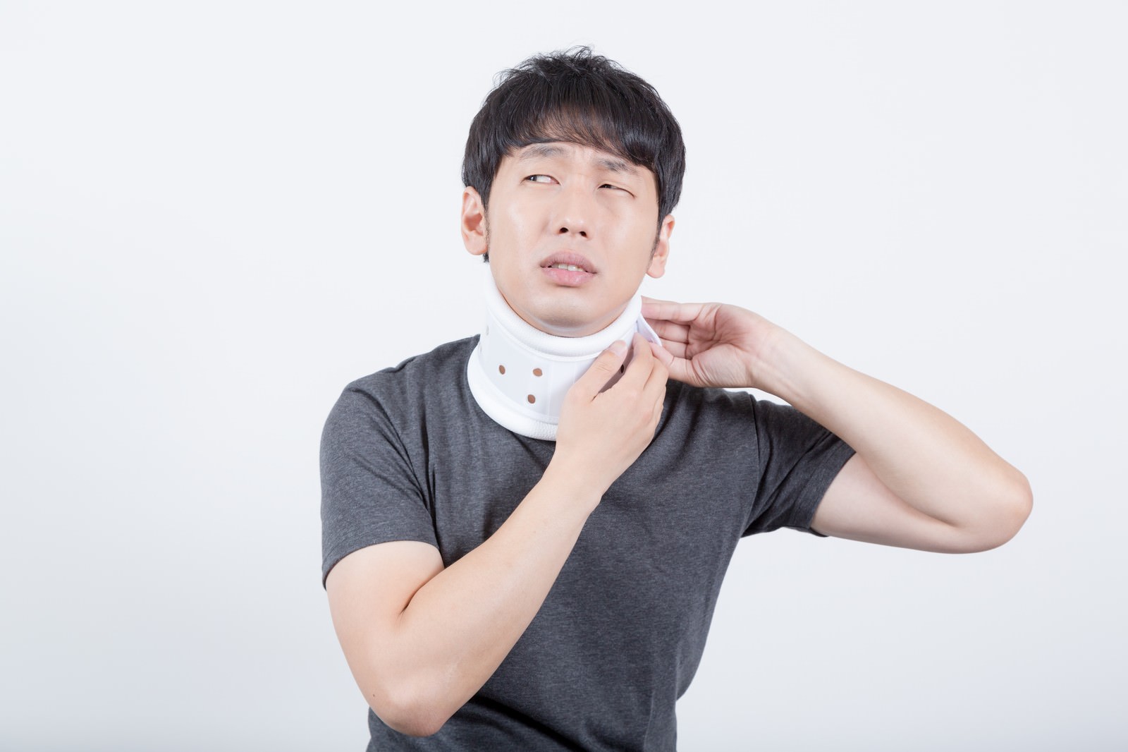 白い頚椎カラーを装着し、首の痛みで苦しむ男性［モデル：大川竜弥］