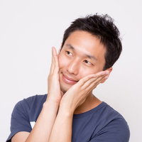 両手で頬を包んで上を見上げる男性の写真