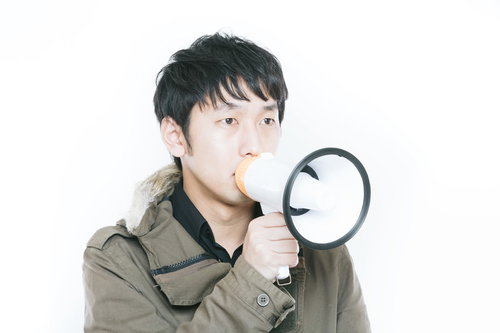 マイクで案内や告知をする男性