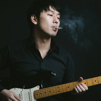 タバコを吸いながらエレキギターを演奏するギタリストの写真