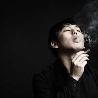 喫煙する眼鏡をかけた男性が口から煙を吐き出すの写真