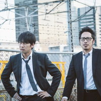 都市の高架下で立ち止まる帰社か直帰か悩む若手営業コンビの写真