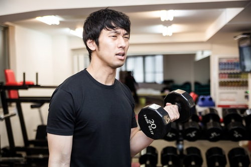 ダンベルカールで上腕二頭筋を鍛える男性トレーニング