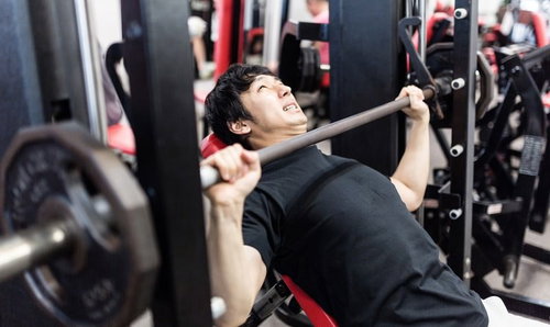 バーベルインクラインベンチプレスで大胸筋上部に刺激を与える男性