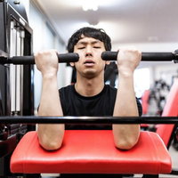 カールマシンで上腕二頭筋をパンプさせる男性のトレーニングの写真