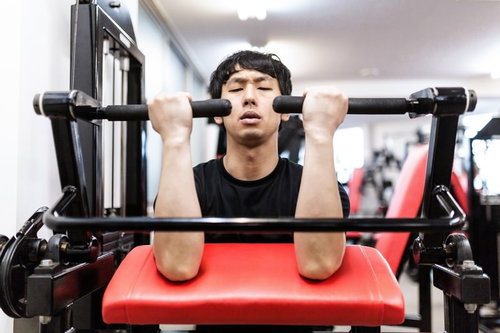 カールマシンで上腕二頭筋をパンプさせる男性のトレーニング