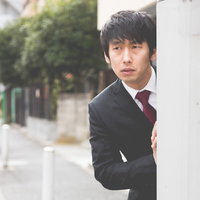 壁の隙間からひとりだるまさんがころんだを覗く男性の写真