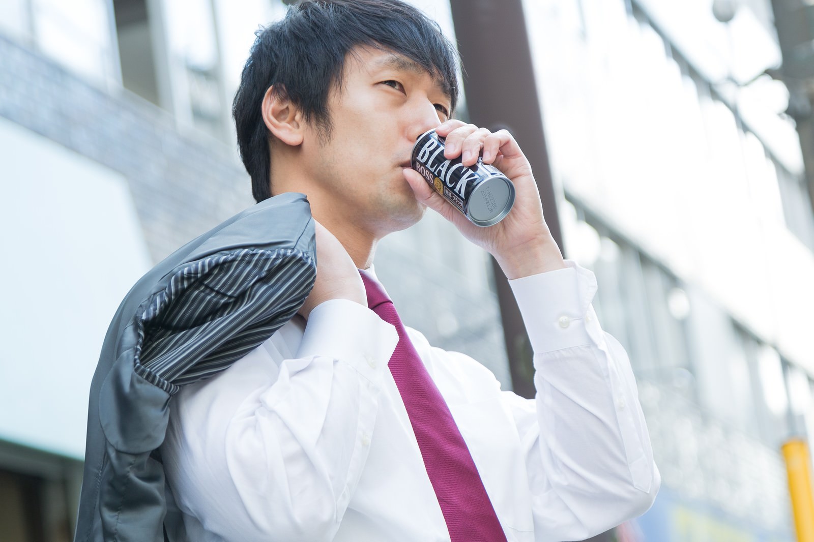 缶コーヒーを飲みながら歩くサラリーマン男性［モデル：大川竜弥］