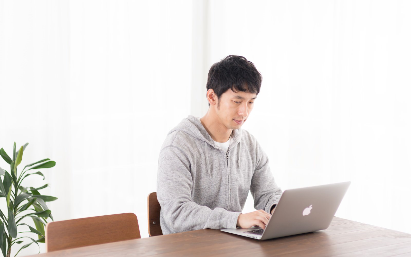 リビングの木製テーブルでノートパソコンを操作する男性［モデル：大川竜弥］