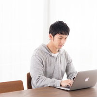 リビングで株価をチェックするデイトレーダーの写真