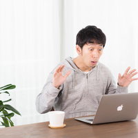 気づいたら資産がマイナスになった瞬間にパソコンの画面を見て驚く男性の写真