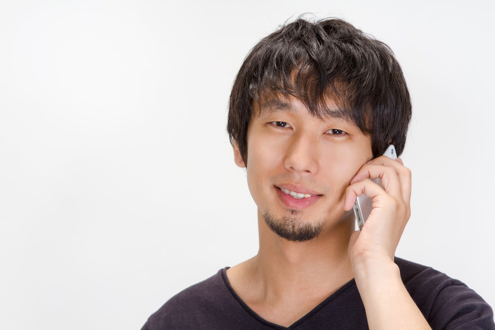 笑顔で携帯電話を耳に当てて通話する男性［モデル：大川竜弥］