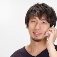 「今何やってるの？」と笑顔で電話する男性の写真