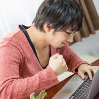 「なんてことだ」と拳を握るプログラマーの写真