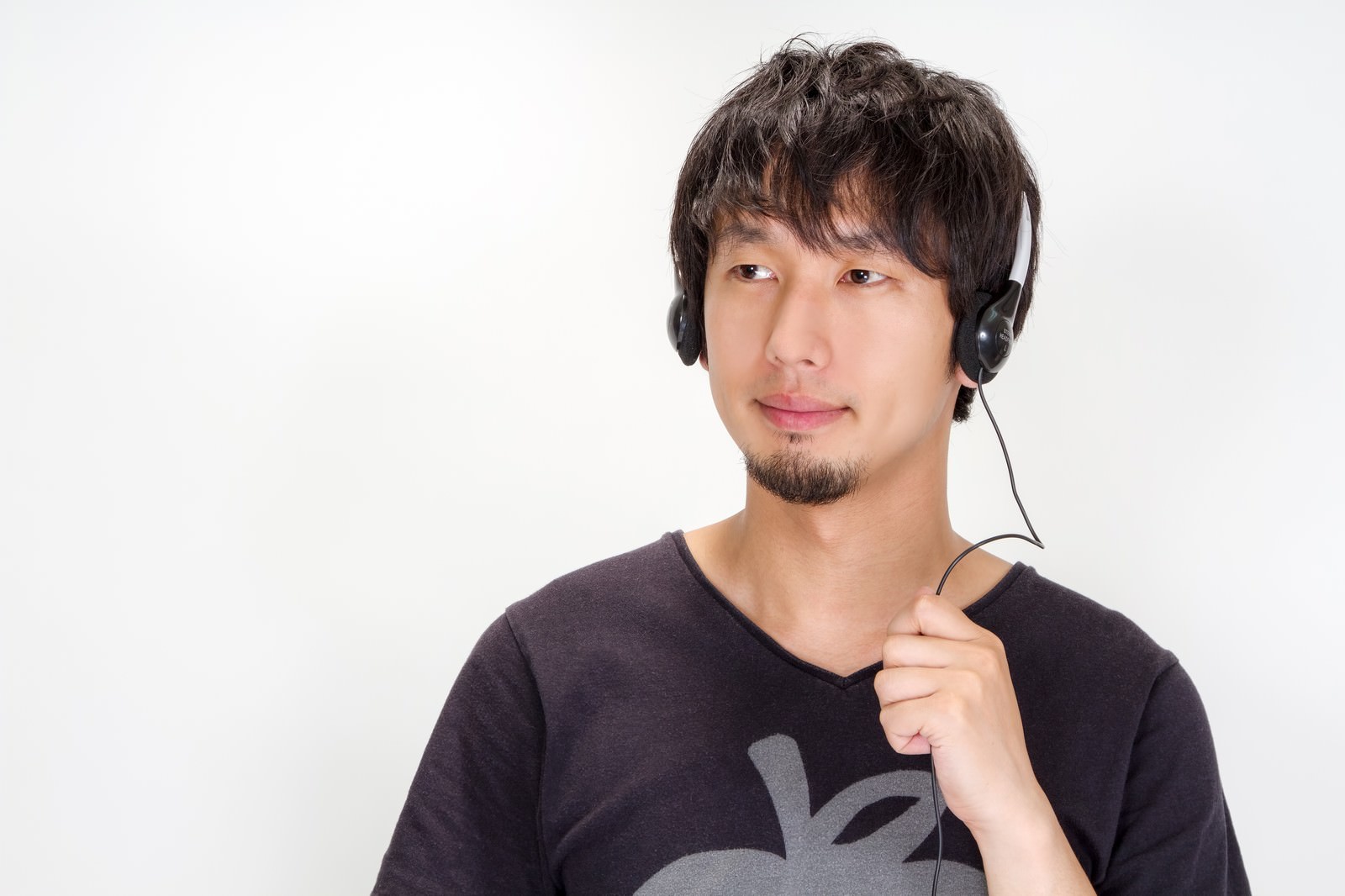 ヘッドセットを手に持つ男性のバストショット［モデル：大川竜弥］