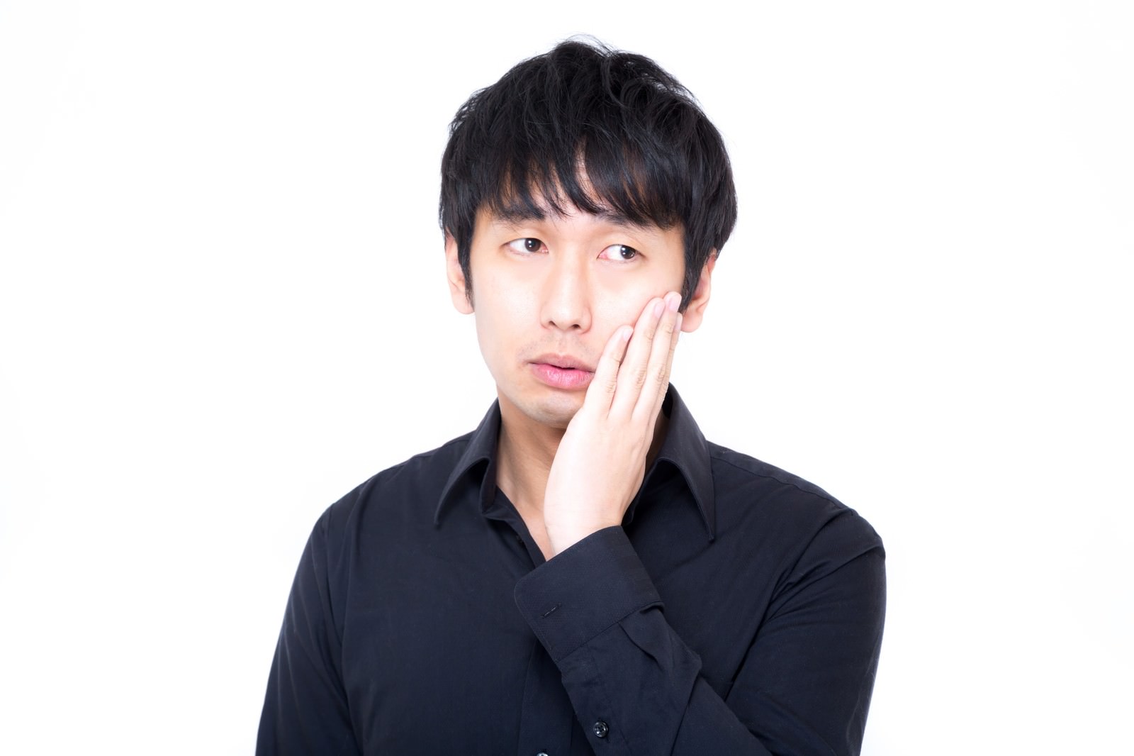 頬に手を当てて視線を外す黒シャツの男性［モデル：大川竜弥］