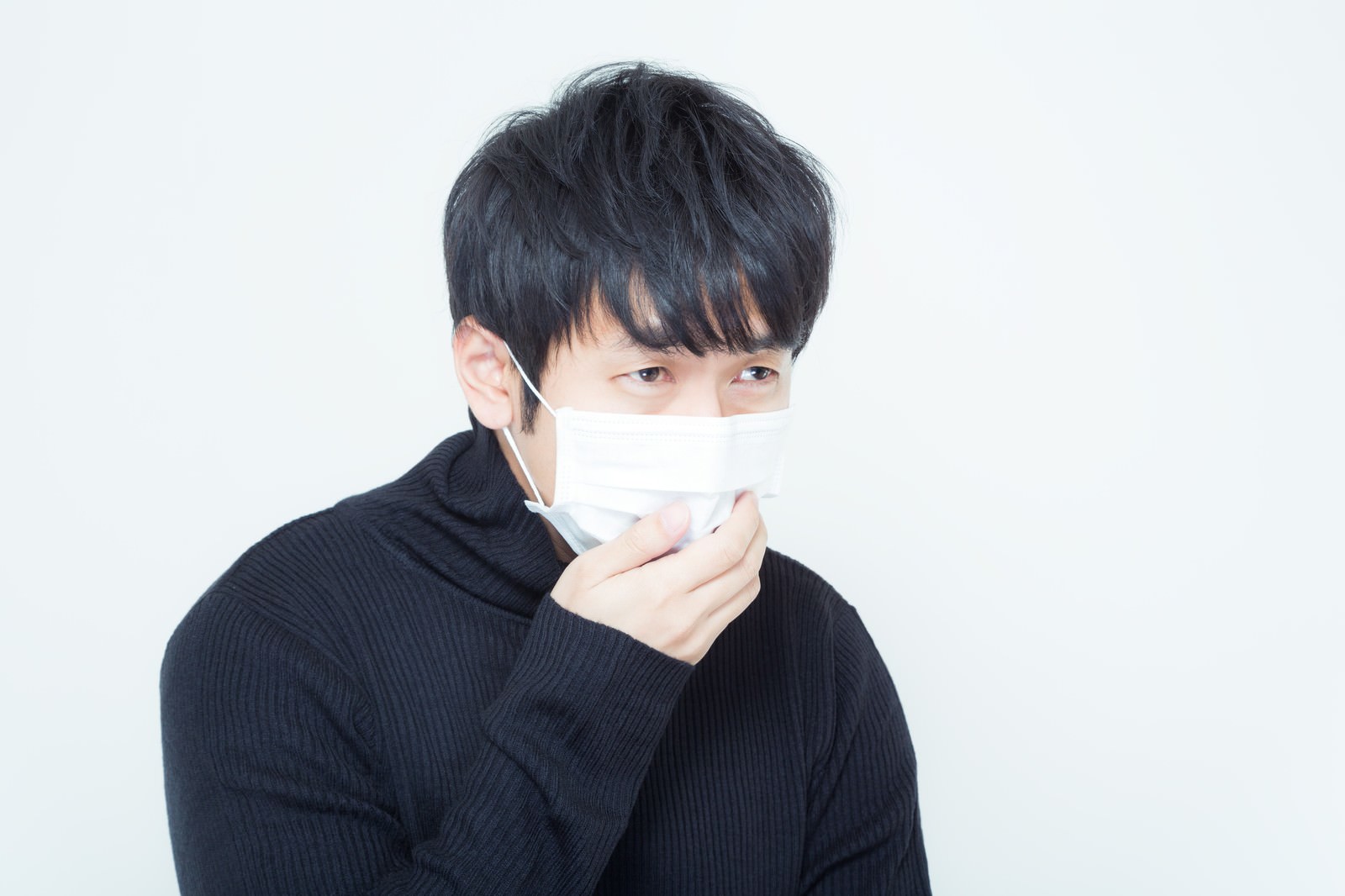 白いマスクを右手で押さえる男性［モデル：大川竜弥］