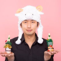 新年！門松を両手に持った羊帽をかぶった男性の写真