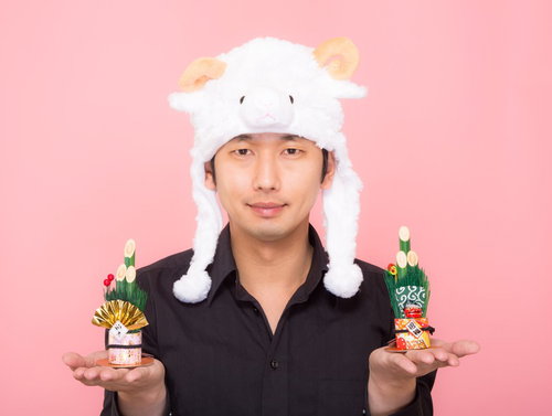 新年！門松を両手に持った羊帽をかぶった男性