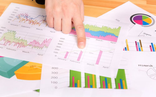 テーブルに広げたグラフ資料を指差す手