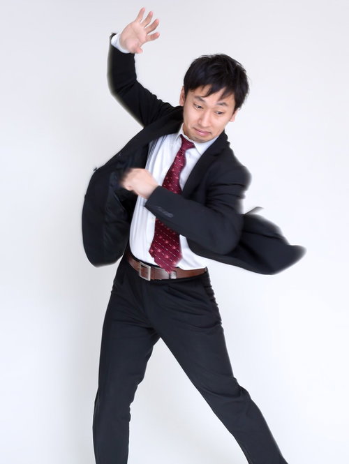 両腕を広げて動き回るスーツ姿の男性