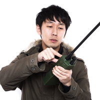 無線機を両手で持って操作するジャケットの男性の写真